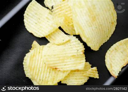 Delicious potato chips closeup on the black