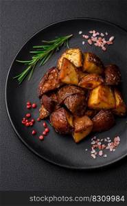 Delicious potatoes baked in their skins with rosemary and spices on a dark concrete background