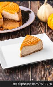 Delicious pumpkin cheesecake in white plate on wooden table