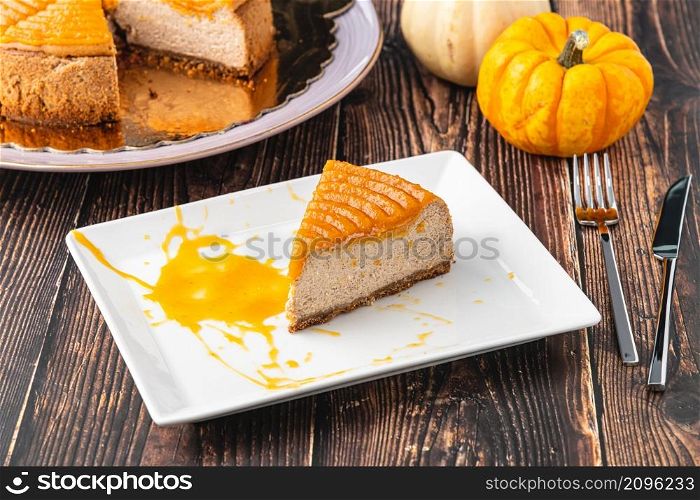 Delicious pumpkin cheesecake in white plate on wooden table