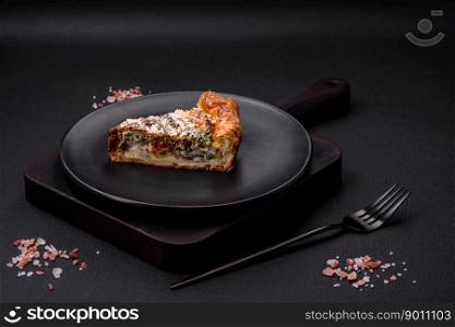 Delicious quiche with chicken, cheese, herbs, spices and herbs on a dark concrete background