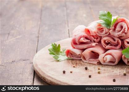 delicious raw ham rolls on wooden table with parsley leaves