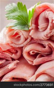 delicious raw ham rolls on wooden table with parsley leaves