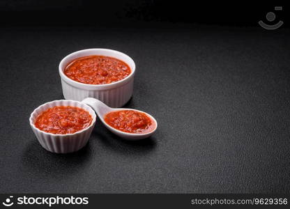 Delicious red Napoletana sauce with onions, salt, spices and herbs in a white bowl on a dark concrete background