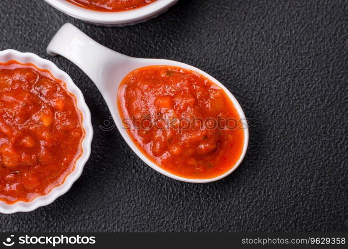 Delicious red Napoletana sauce with onions, salt, spices and herbs in a white bowl on a dark concrete background