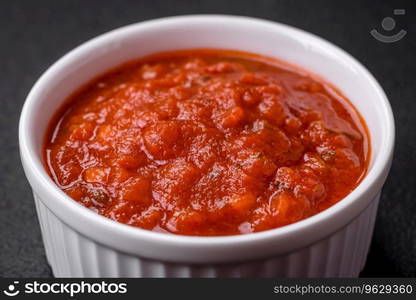 Delicious red Napoletana sauce with onions, salt, spices and herbs in a white bowl on a dark concrete background