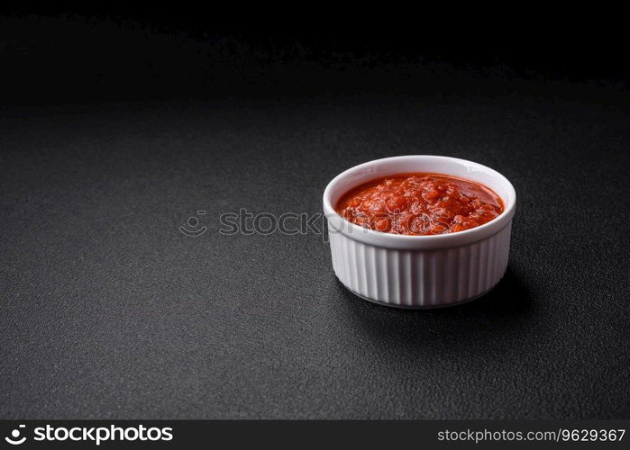 Delicious red Napoletana sauce with onions, salt, spices and herbs in a white bowl on a dark concrete background