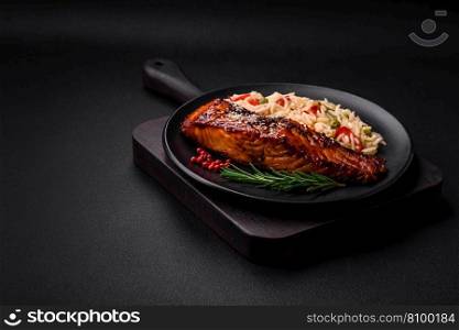 Delicious red salmon fish grilled with sauce and sesame seeds with rice, vegetables, spices and herbs on a dark concrete background