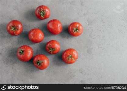 Delicious red tomatoes for making ketchup on grey background. Vegetables covered with water drops. Freshness and nutrition concept. Horizontal shot