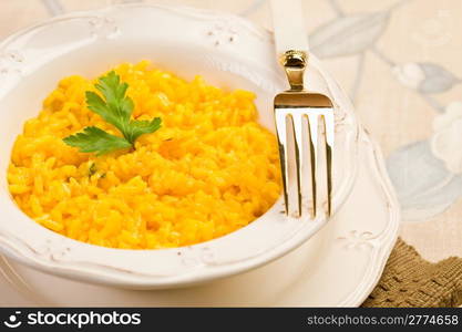 delicious risotto with saffron and golden fork on elegant table