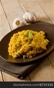 delicious risotto with saffron on wooden table with garlic and napkin