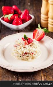 Delicious risotto with strawberries on wooden table