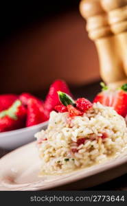 Delicious risotto with strawberries on wooden table