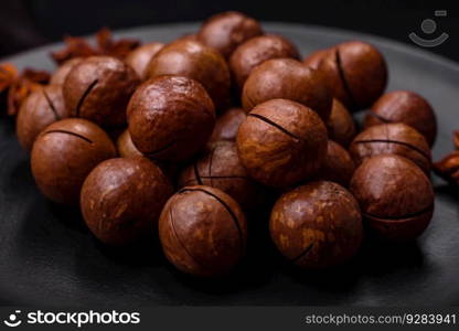 Delicious roasted macadamia nuts in shell on a dark textured concrete background. Vegetarian food