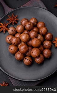 Delicious roasted macadamia nuts in shell on a dark textured concrete background. Vegetarian food