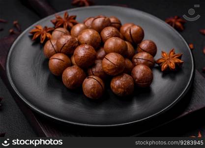 Delicious roasted macadamia nuts in shell on a dark textured concrete background. Vegetarian food