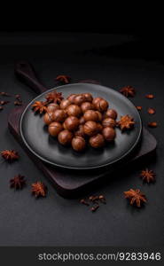 Delicious roasted macadamia nuts in shell on a dark textured concrete background. Vegetarian food