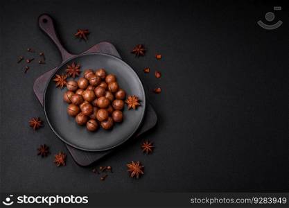 Delicious roasted macadamia nuts in shell on a dark textured concrete background. Vegetarian food