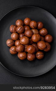 Delicious roasted macadamia nuts in shell on a dark textured concrete background. Vegetarian food