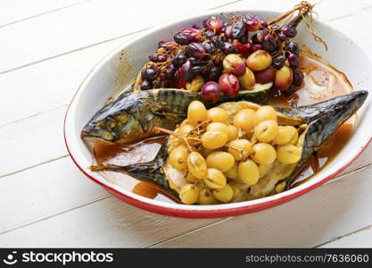 Delicious roasted mackerel fish in a baking dish with grape berry sauce. Baked fish with grape sauce
