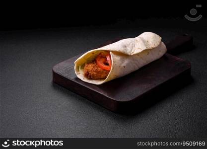 Delicious roll with chicken nuggets, tomatoes, lettuce and sauces with salt and spices on a dark concrete background