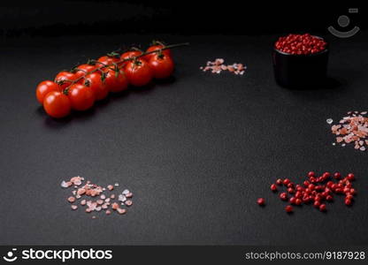 Delicious salad of fresh cherry tomatoes, sweet peppers, broccoli and cauliflower with salt and spices on a dark concrete background