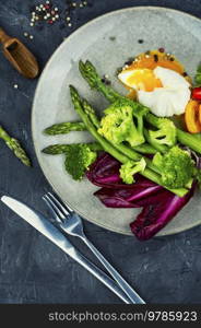 Delicious salad with asparagus, lettuce, broccoli and poached egg.. Fresh salad of asparagus, lettuce and poached eggs.