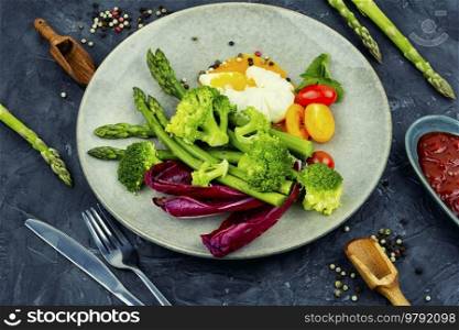 Delicious salad with asparagus, lettuce, fresh tomatoes and poached egg. Healthy balanced eating. Healthy salad of asparagus, lettuce and poached eggs.
