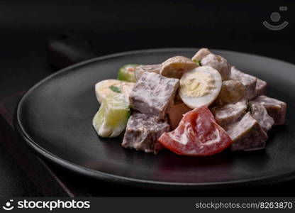 Delicious salad with boiled beef tongue, quail eggs, tomatoes and cucumber on a dark concrete background