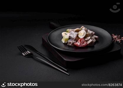 Delicious salad with boiled beef tongue, quail eggs, tomatoes and cucumber on a dark concrete background