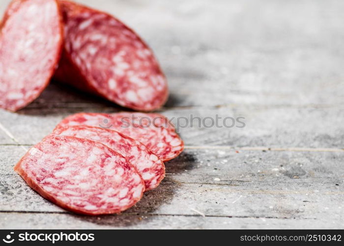 Delicious salami sausage on the table. On a gray background. High quality photo. Delicious salami sausage on the table.