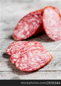 Delicious salami sausage on the table. On a gray background. High quality photo. Delicious salami sausage on the table.