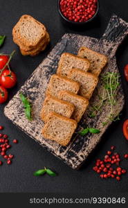 Delicious salted rectangular wheat croutons with salt and spices on a dark concrete background