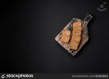 Delicious salted rectangular wheat croutons with salt and spices on a dark concrete background