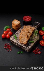 Delicious salted rectangular wheat croutons with salt and spices on a dark concrete background