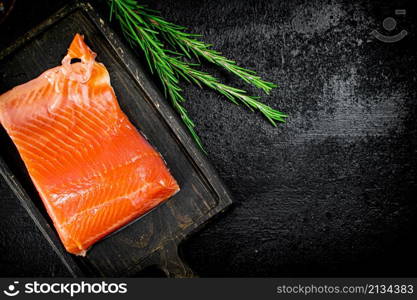 Delicious salted salmon on a cutting board. On a black background. High quality photo. Delicious salted salmon on a cutting board.