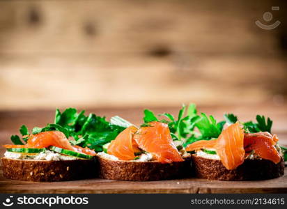 Delicious sandwich with salmon and parsley. On a wooden background. High quality photo. Delicious sandwich with salmon and parsley.