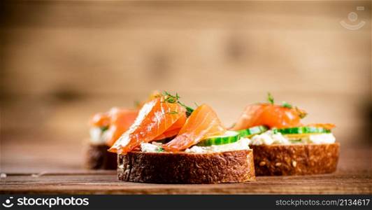 Delicious sandwich with salmon and parsley. On a wooden background. High quality photo. Delicious sandwich with salmon and parsley.