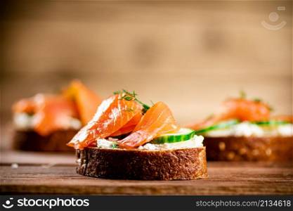 Delicious sandwich with salmon and parsley. On a wooden background. High quality photo. Delicious sandwich with salmon and parsley.