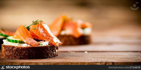 Delicious sandwich with salmon and parsley. On a wooden background. High quality photo. Delicious sandwich with salmon and parsley.