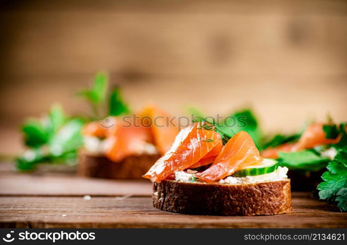 Delicious sandwich with salmon and parsley. On a wooden background. High quality photo. Delicious sandwich with salmon and parsley.