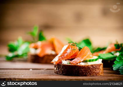 Delicious sandwich with salmon and parsley. On a wooden background. High quality photo. Delicious sandwich with salmon and parsley.