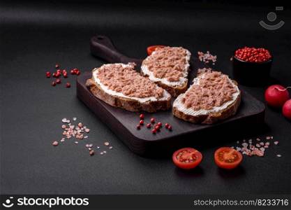 Delicious sandwiches consisting of grilled toast, canned tuna and cream cheese on a dark concrete background