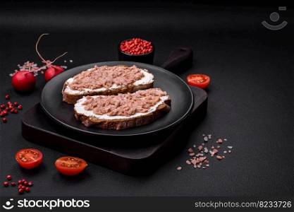 Delicious sandwiches consisting of grilled toast, canned tuna and cream cheese on a dark concrete background