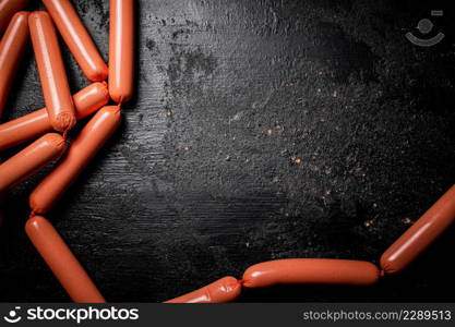 Delicious sausages boiled on the table. On a black background. High quality photo. Delicious sausages boiled on the table.
