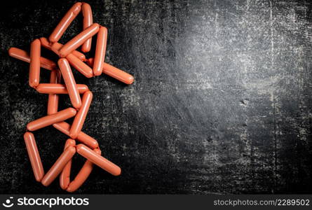 Delicious sausages on the table. On a black background. High quality photo. Delicious sausages on the table.