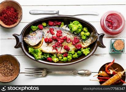Delicious sea bream baked with raspberries and broccoli.. Tasty gilthead fish in berry sauce.