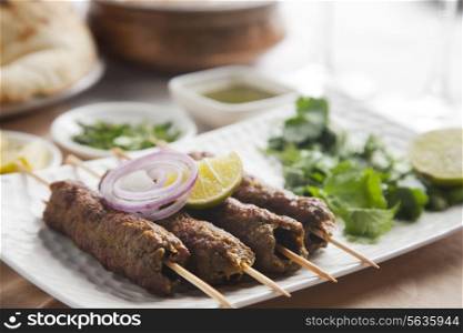 Delicious seekh kabab garnished with lime and onion in plate