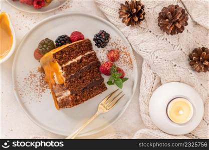 Delicious semi-naked chocolate cake with caramel topping and decorated with blackberries and raspberries. Light background