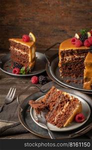 Delicious semi-naked chocolate cake with caramel topping and decorated with blackberries and raspberries. Dark background